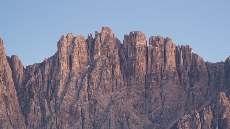 Pale Dolomite towers glowing at dusk above a sea of cloud and dark forest
