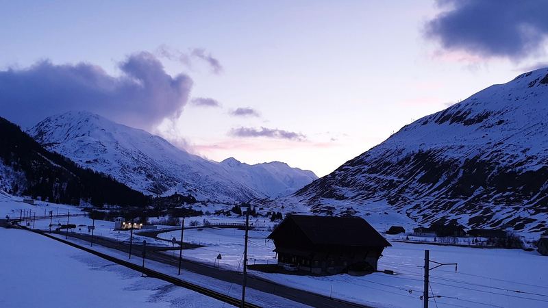 Dusk over the snowy Urseren valley, an old wooden barn in the foreground and the mountains glowing pink