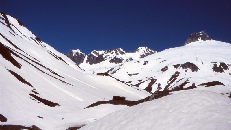 Deep spring snow in a high valley below dark rocky peaks and a cobalt sky