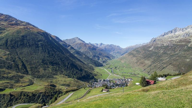 Andermatt and the green Urseren valley seen from the hairpins of the Oberalp road, mountains on every side