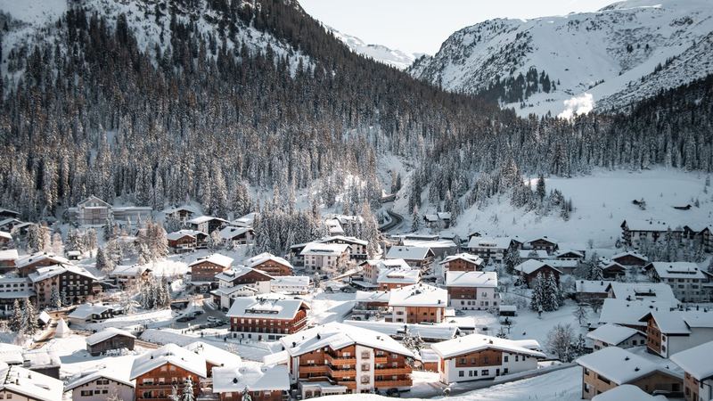 The chalets and hotels of Lech deep in snow below the forest and the peaks