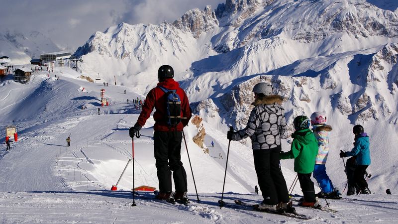 A family of skiers looking out over the pistes and the snowy peaks of the Three Valleys