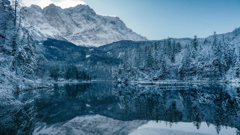 The Zugspitze reflected in the still Eibsee among snow-laden firs
