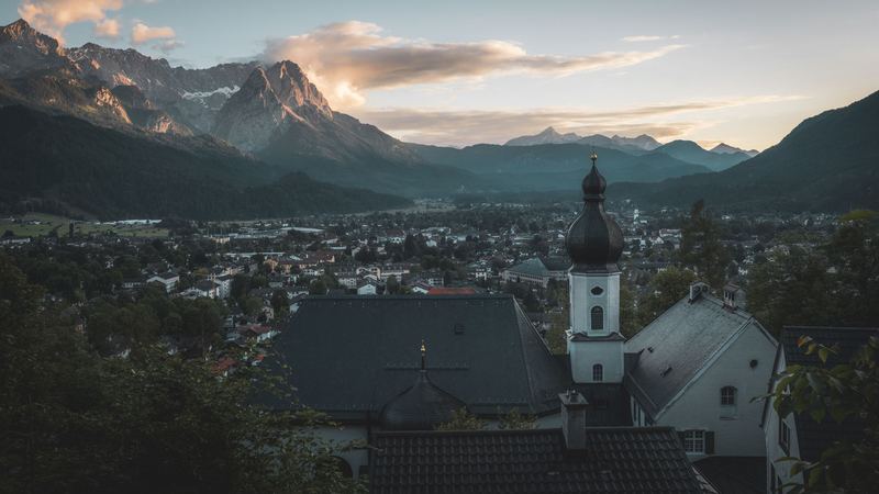 The onion-domed church and roofs of Garmisch-Partenkirchen below the Wetterstein peaks at sunset