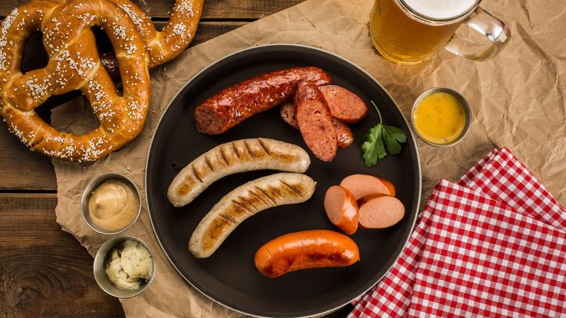 Bavarian sausages with pretzels, sweet mustard and a mug of beer on a wooden table