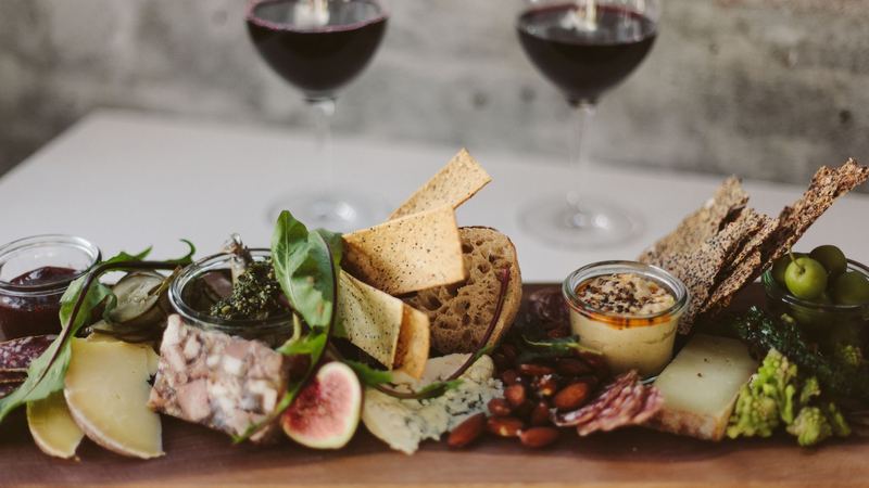 A board of cheeses, terrine, figs and charcuterie before two glasses of red wine