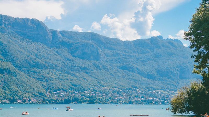Lake Annecy in summer below green mountains and a blue sky