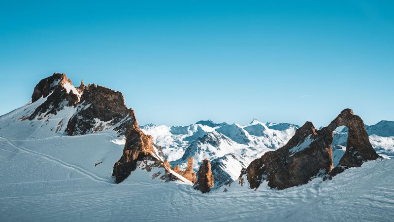 Fresh snowfields and rock spires under a clear blue sky above Val d'Isère