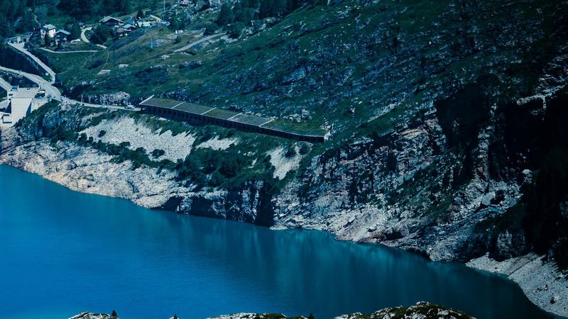 The turquoise Lac du Chevril below steep green slopes, on the road to Val d'Isère