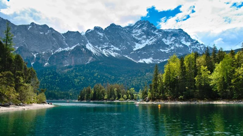 The turquoise Eibsee below the snow-streaked wall of the Zugspitze in early summer