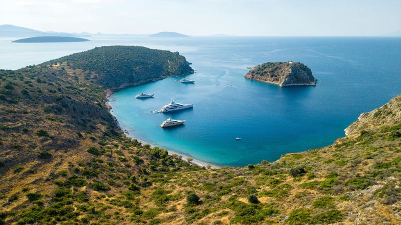 Superyachts at anchor in a turquoise bay near Tolo in the Peloponnese