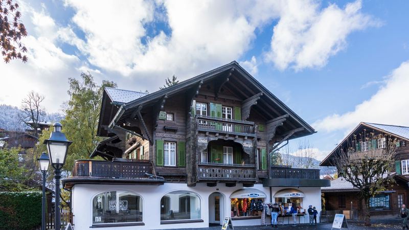 Chalet Naegeli, a carved wooden chalet with green shutters and a gallery on the ground floor, in Gstaad