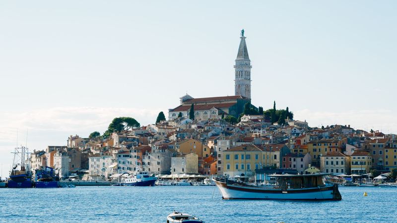 Rovinj's pastel houses and the bell tower of St. Euphemia above a blue harbour in Istria
