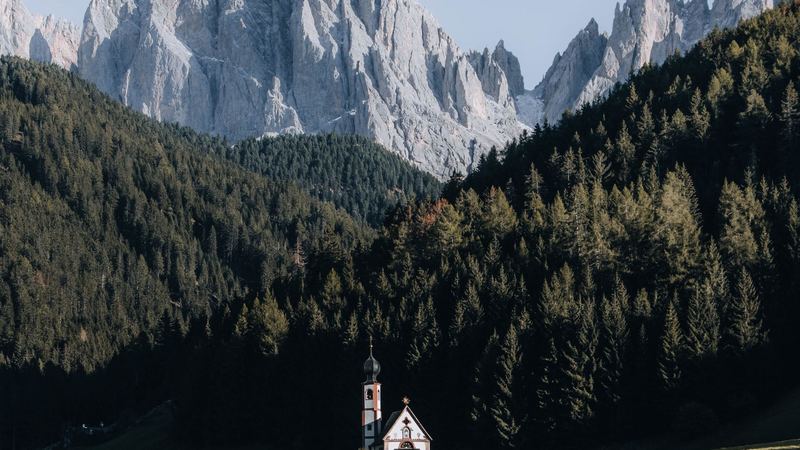 The church of St. Johann in Ranui in a green meadow below the Odle peaks, Val di Funes