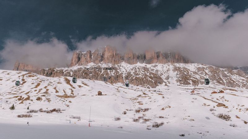 Gondolas crossing the snowfields below the towers of the Sella