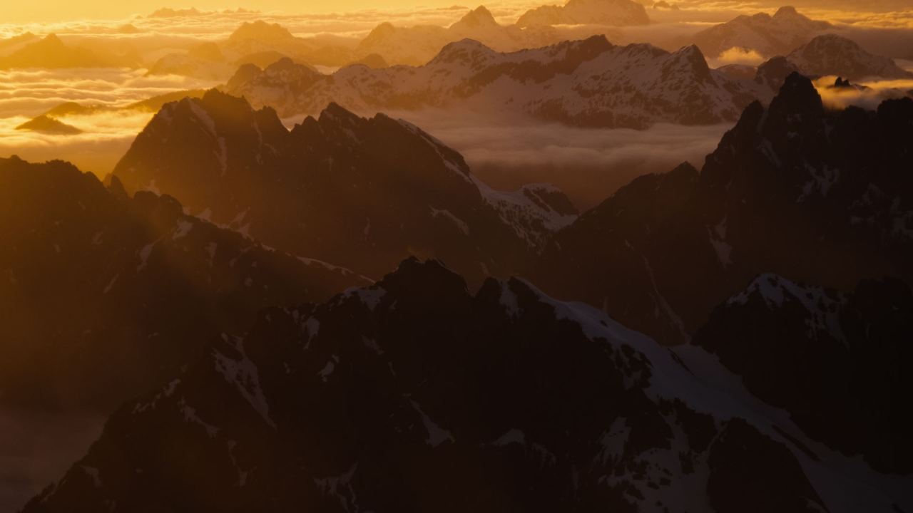 Ridge after ridge of high peaks rising from a sea of cloud in golden evening light