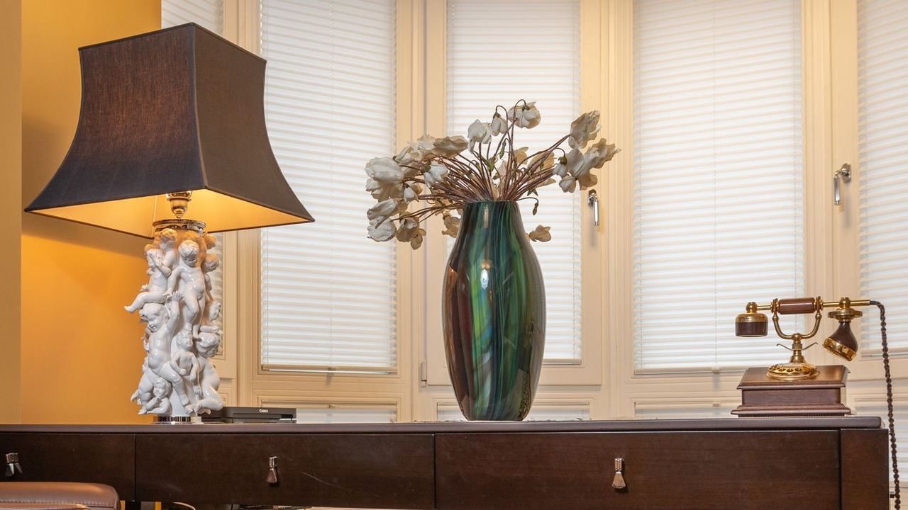 A lamp, a vase and an old telephone on a sideboard