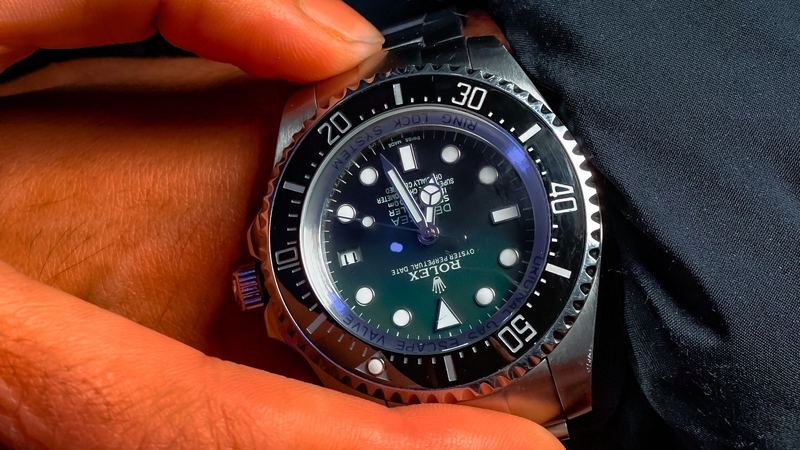 A Swiss diver’s watch held in the hand against a dark down jacket