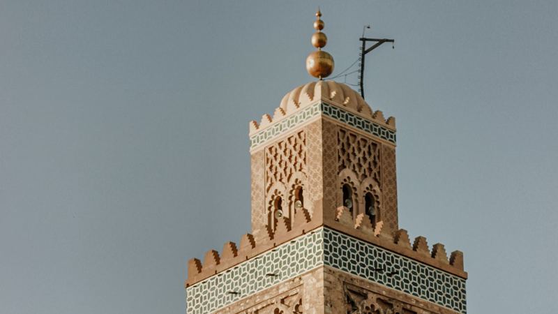 The top of the Koutoubia minaret in Marrakech, with its gold finials and green tile band against the sky