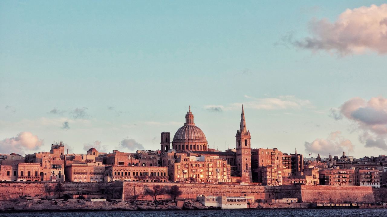 Valletta's dome and spire rising above its sea walls at sunset