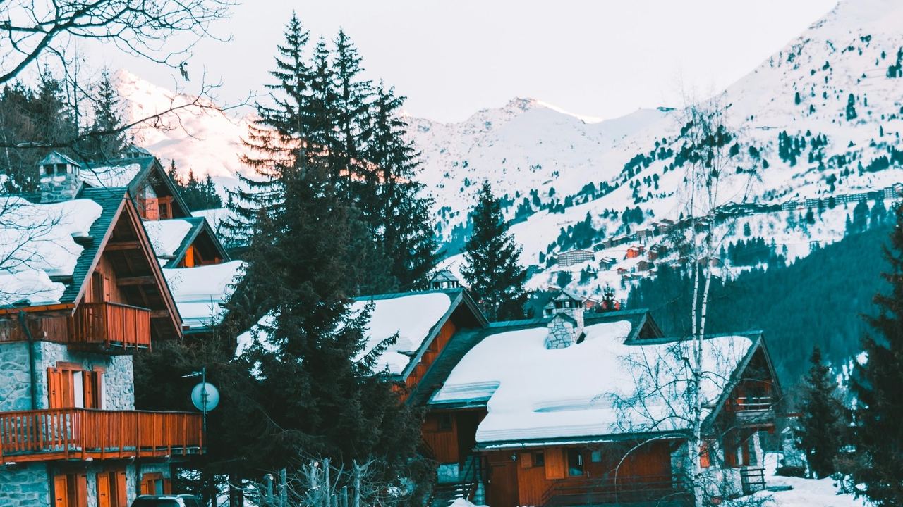 Snow-covered wooden chalets of Méribel below the forested slopes