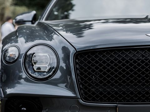 A grey Bentley Continental GT, its round lamps and diamond-quilted grille close up