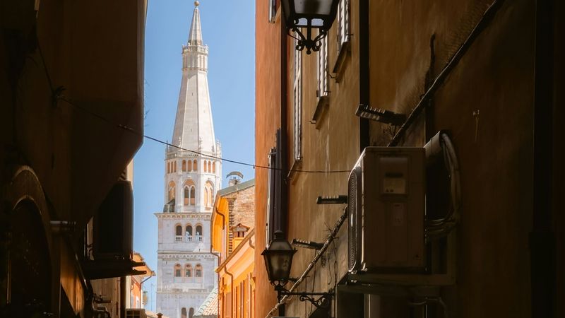 The Ghirlandina, the cathedral tower of Modena, at the end of a narrow street