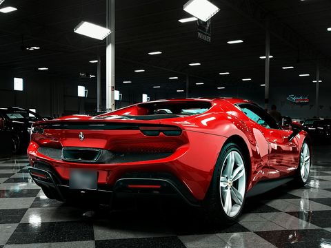 A red Ferrari 296 GTB on a chequered showroom floor