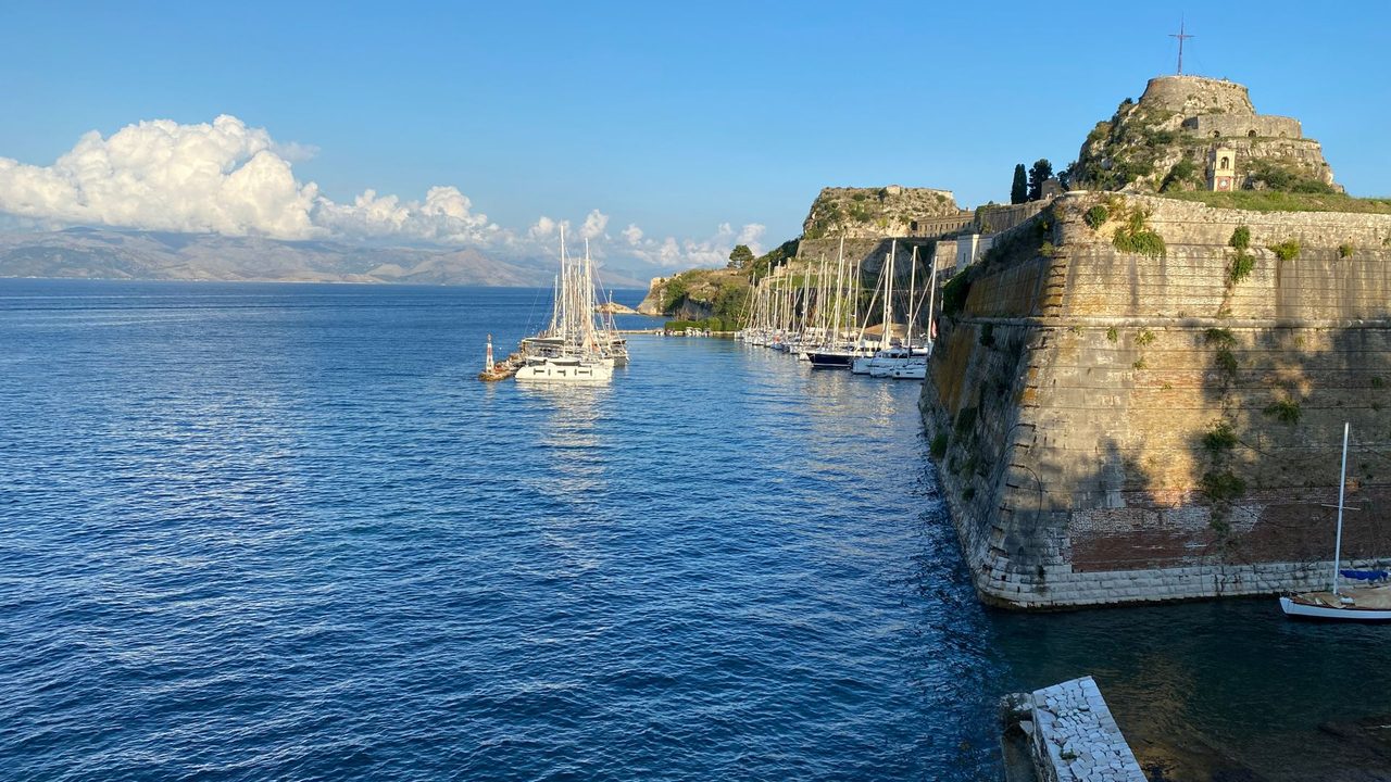 The Old Fortress of Corfu and its yachts on the blue sea, the mountains of Epirus beyond
