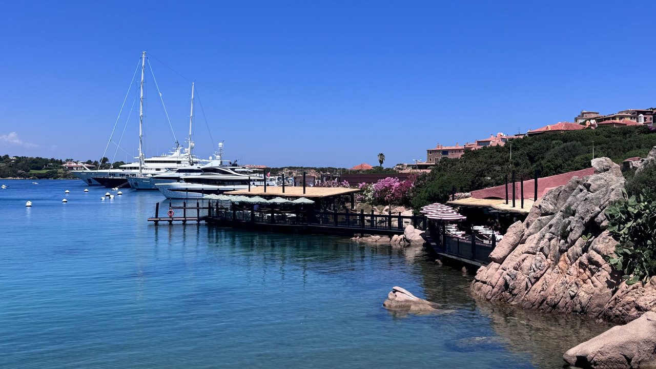 Superyachts in the bay at Porto Cervo, pink granite and bougainvillea on the shore