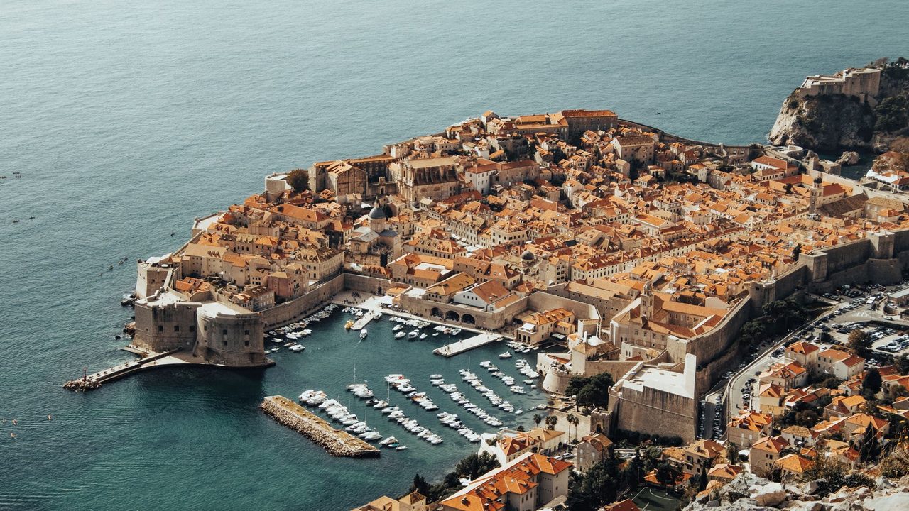 The walled Old Town of Dubrovnik and its old harbour from Mount Srd, Fort Lovrijenac on the cliff beyond