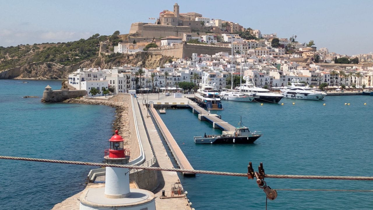 Dalt Vila above Ibiza harbour, superyachts below and the red-topped lighthouse in front