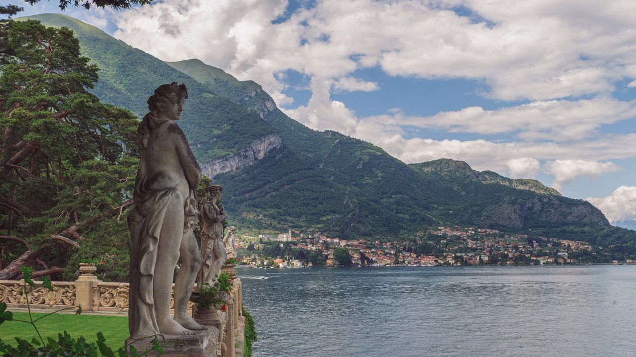 Statues on the balustrade of Villa del Balbianello above Lake Como, the mountains and lakeside villages beyond