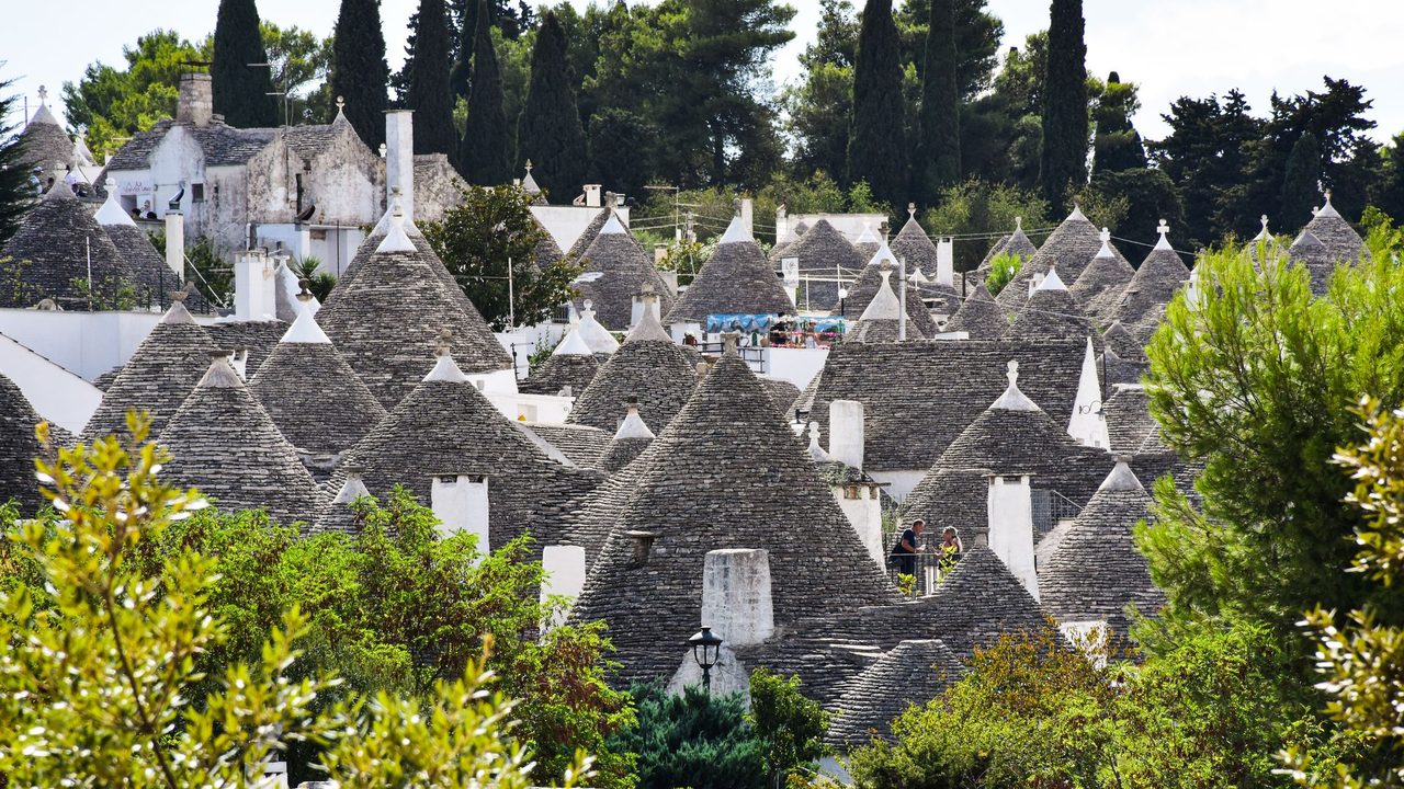 The cone roofs of the trulli of Alberobello among cypresses and pines, Puglia