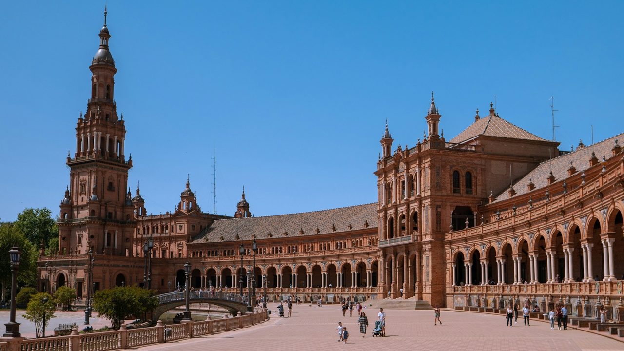 The Plaza de España in Seville, its tower and brick arcades under a blue sky