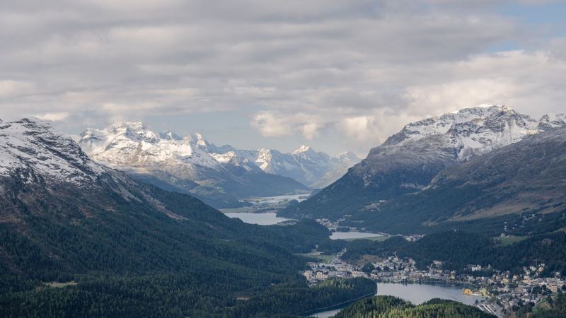 St. Moritz and its lake below the forests, with the lakes of the Upper Engadine stretching away beneath snowy peaks