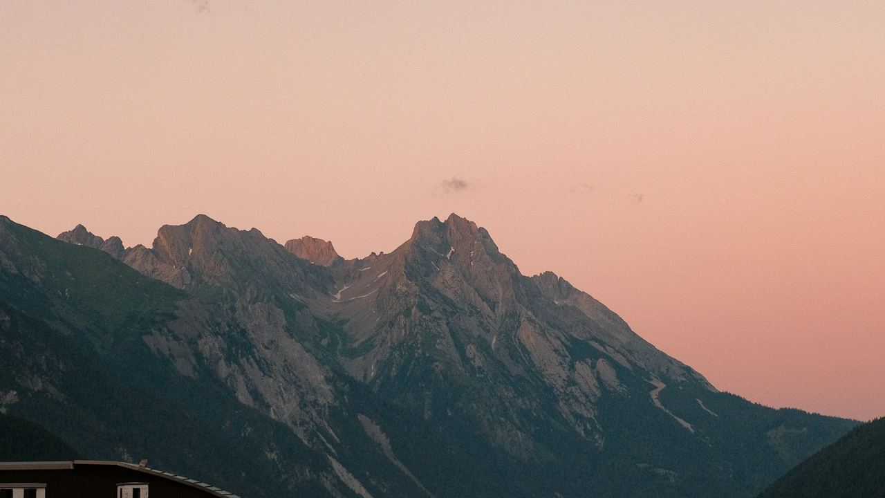 The Arlberg peaks above the valley at St. Anton on a summer evening, the sky turning pink