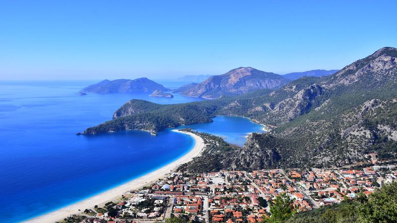 The blue lagoon and long white beach of Ölüdeniz below pine-covered mountains on the Turquoise Coast
